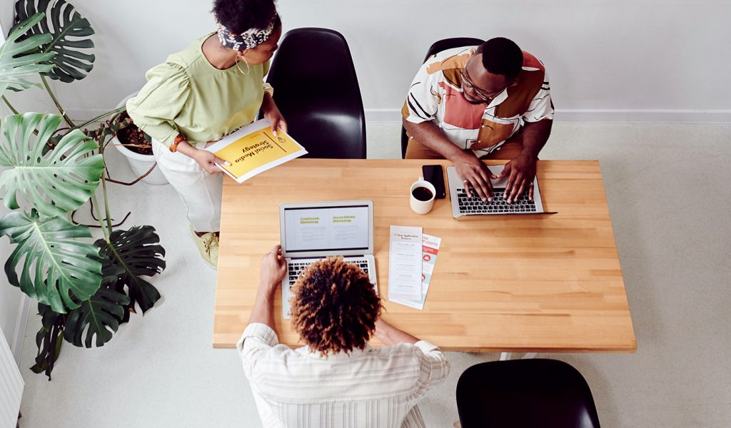 Three creators sitting around a table, working on a book marketing campaign