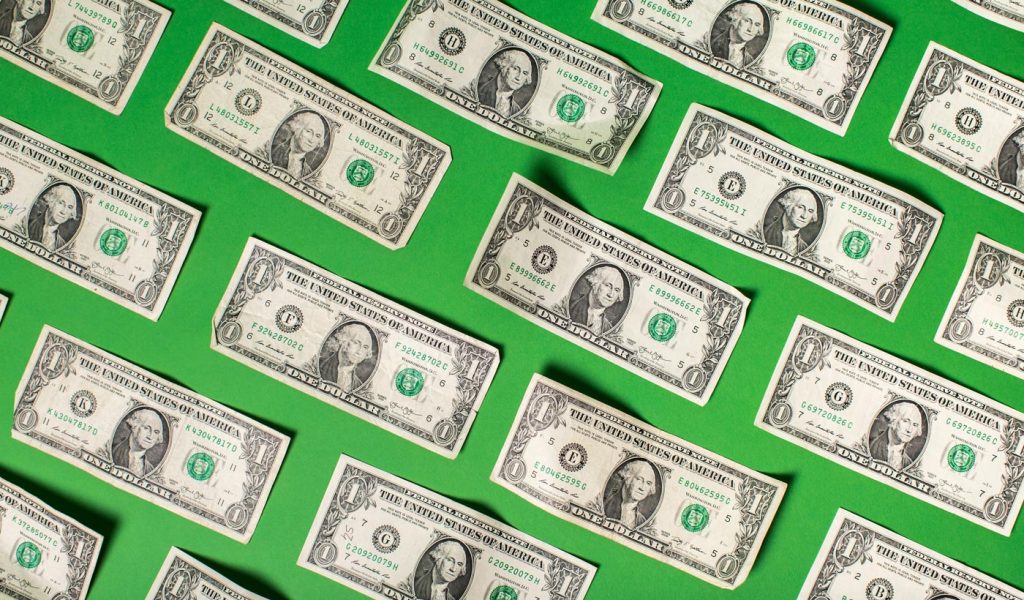 Multiple dollar bills side-by-side with green background