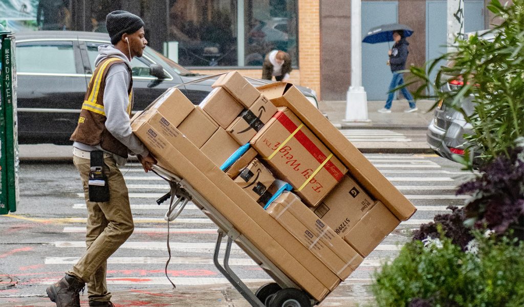 Delivery driver crossing the street with a huge number of packages