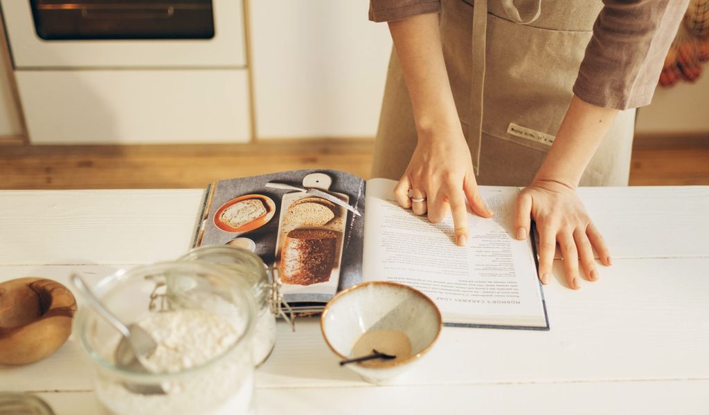 Person following a recipe in a cookbook.