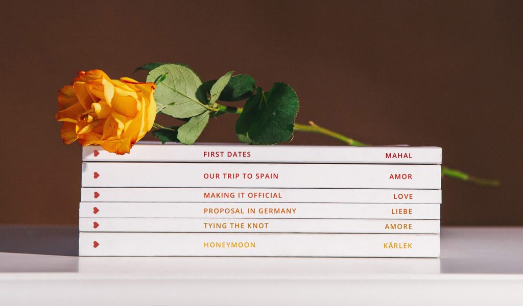 A stack of photo books with titles like "First dates" and "Our trip to Spain."