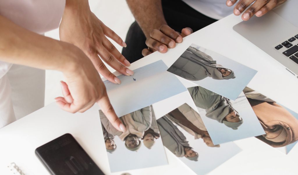 Two photographers looking over printed photographs to pick their favorite.