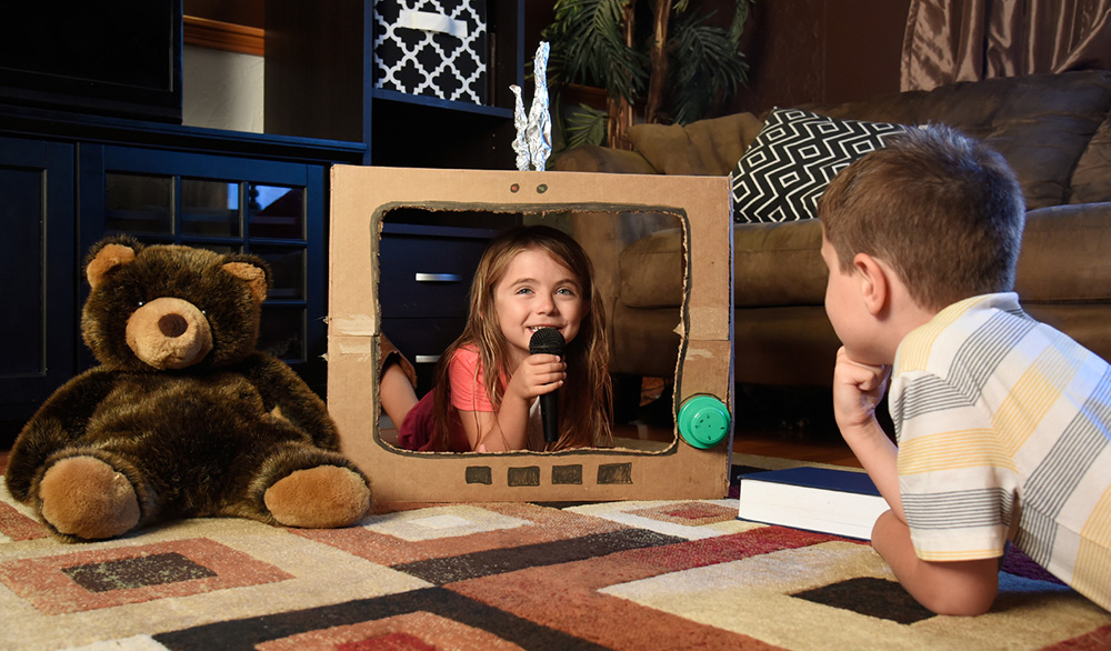 Two kids at home acting out their favorite scene from a book