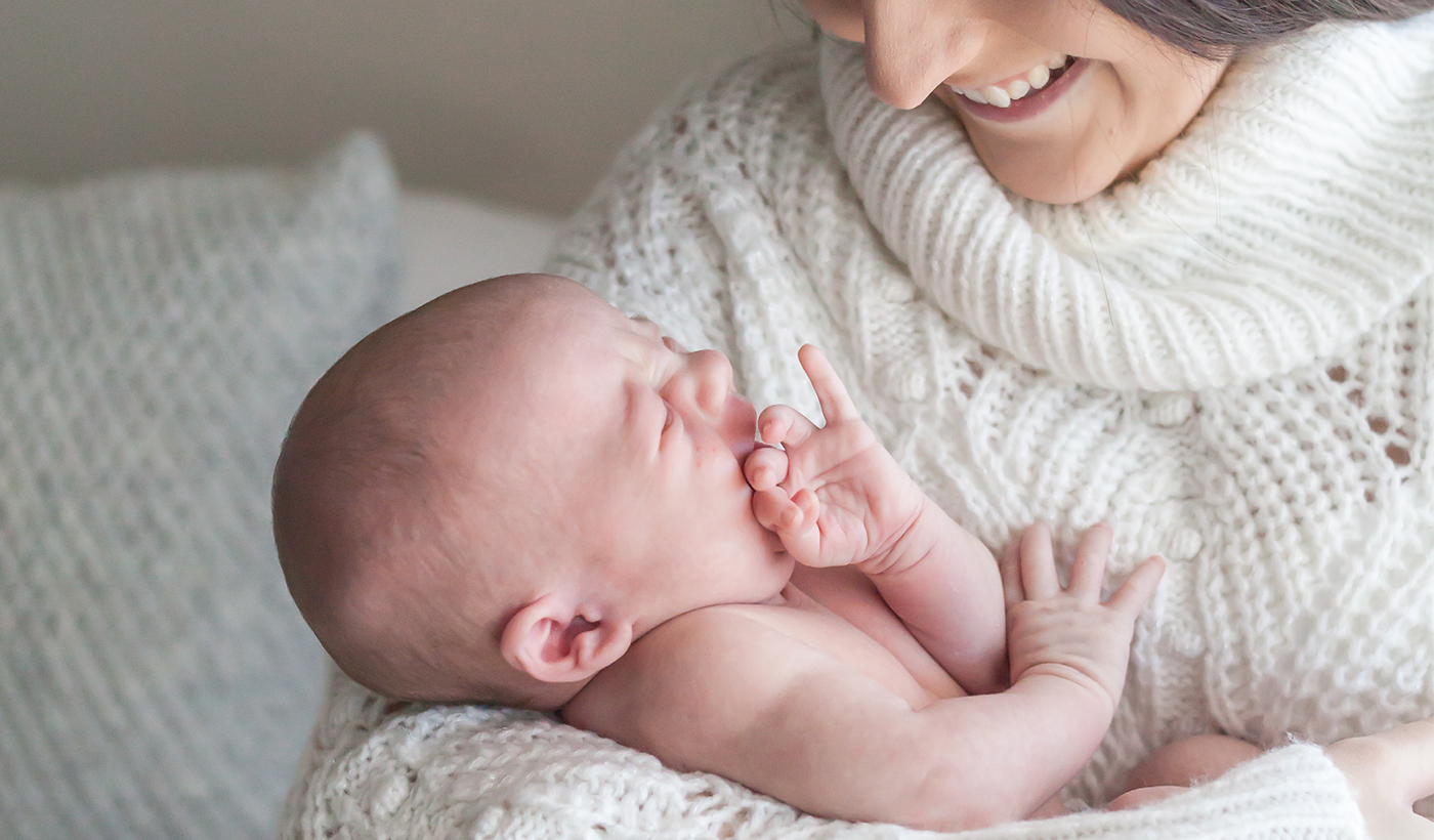 A woman smiling down at a newborn baby