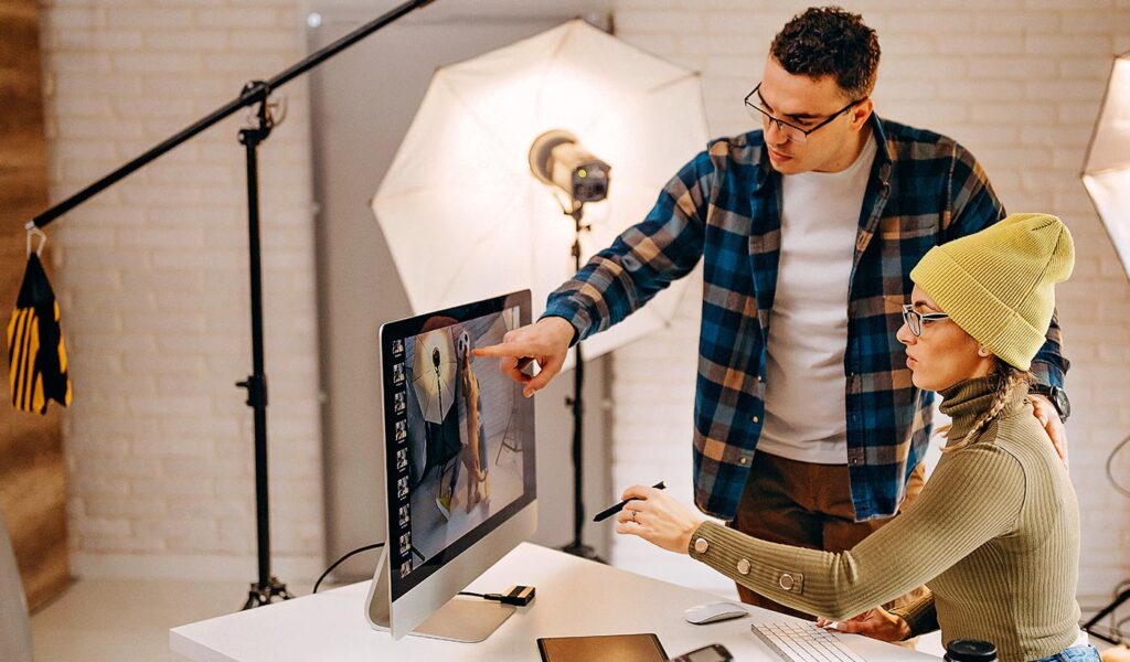 Mentor showing mentee photographs on a computer monitor.