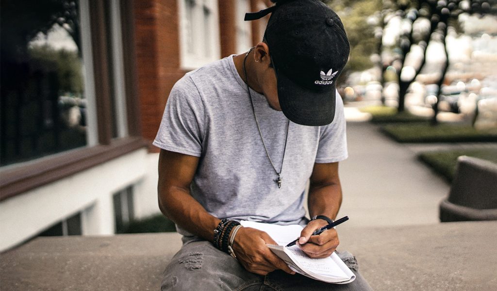 Male sitting outside writing poetry