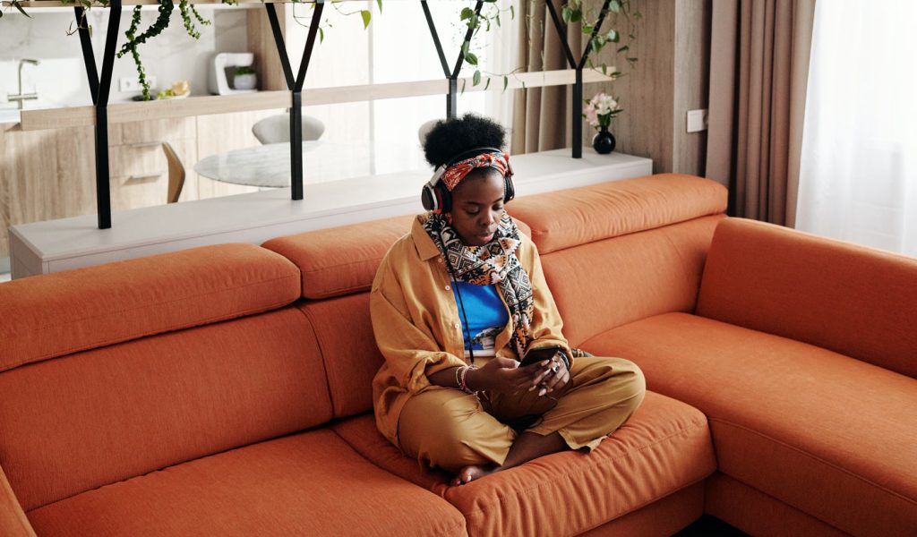 Person sitting on an orange couch listening to an audiobook.