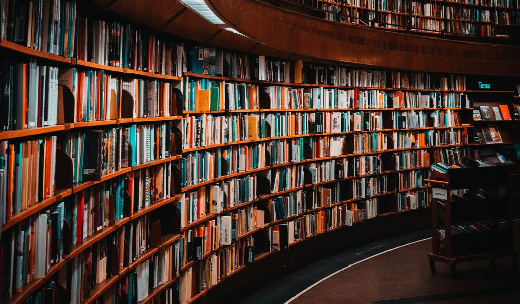 A curved wall of books in a bookstore, featuring popular book genres