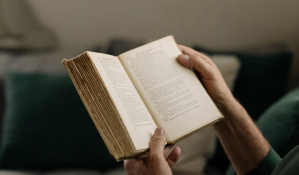 Two hands holding a novel open