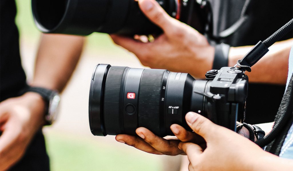 Multiple people holding DSLR cameras with large lenses