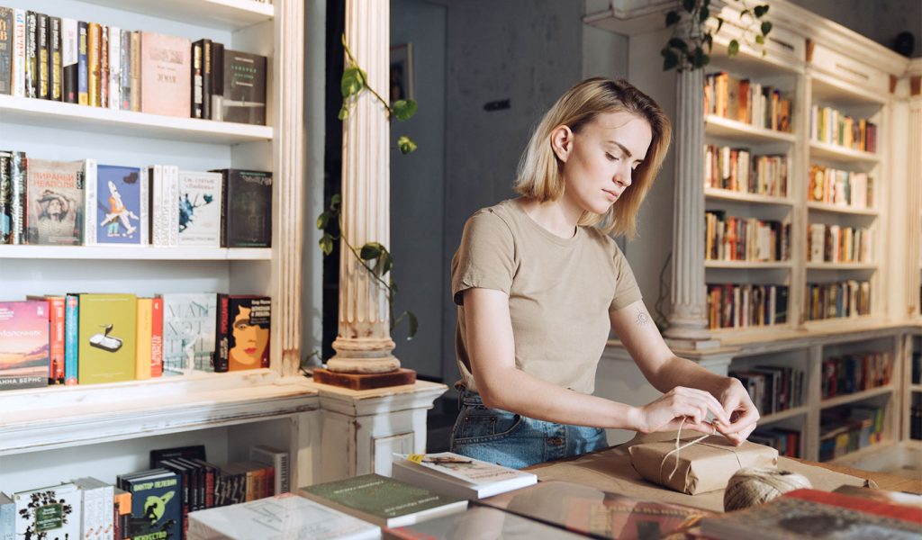 Person wrapping up a book in brown paper to sell it