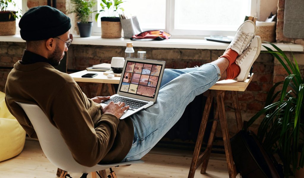 Photographer working on their brand on a laptop with their feet up on a desk