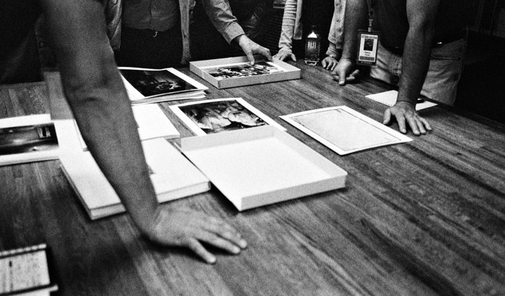 Group of individuals critiquing black and white photographs