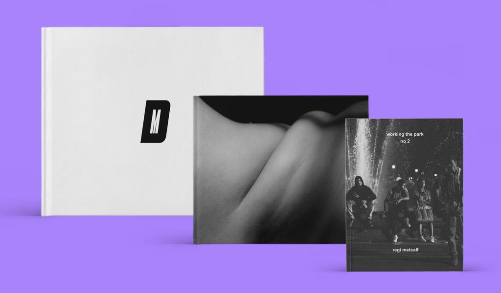 Three black and white photo books standing displayed against a purple background