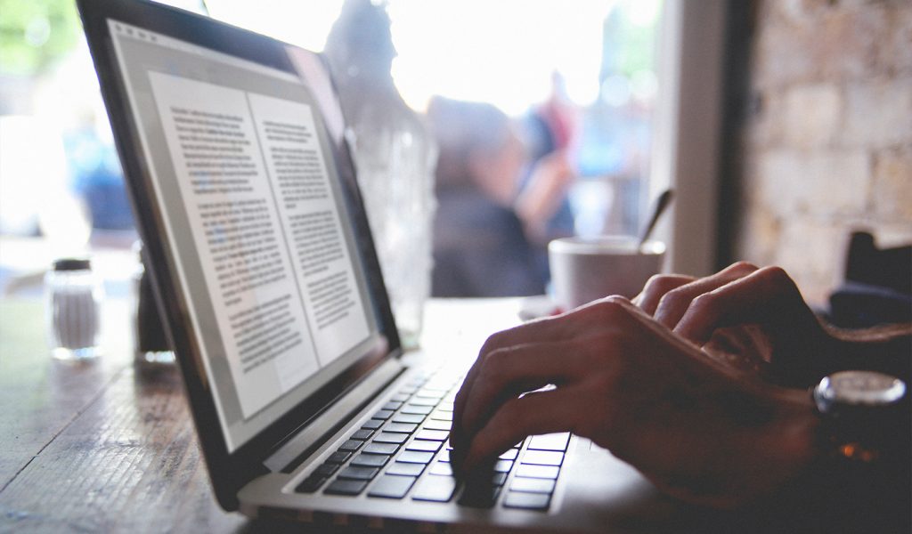 Person working on a laptop on their printed book.