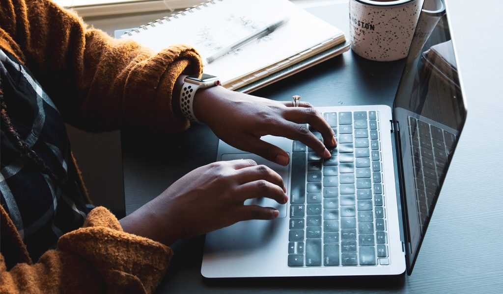 Person typing on a laptop, making a coffee table book