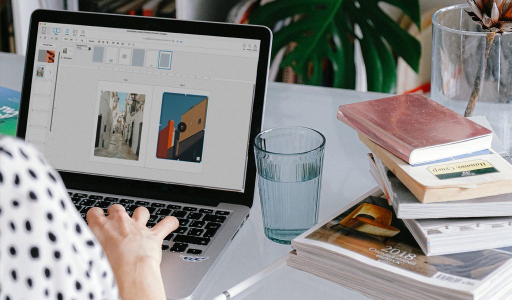 Creator making a coffee table book in BookWright, with a stack of book next to their laptop