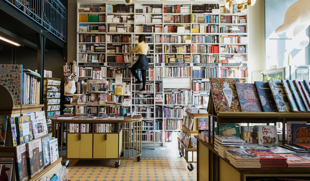 A large bookstore with a ton of low-content books and a person on a ladder