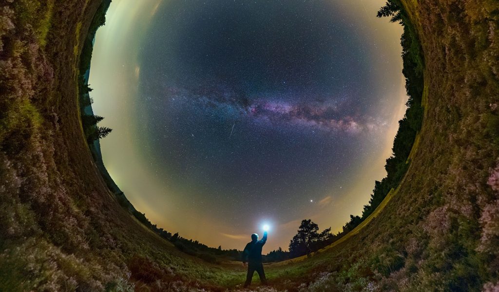 Person holding a glowing orb up to the sky, which looks like a strange orb as well