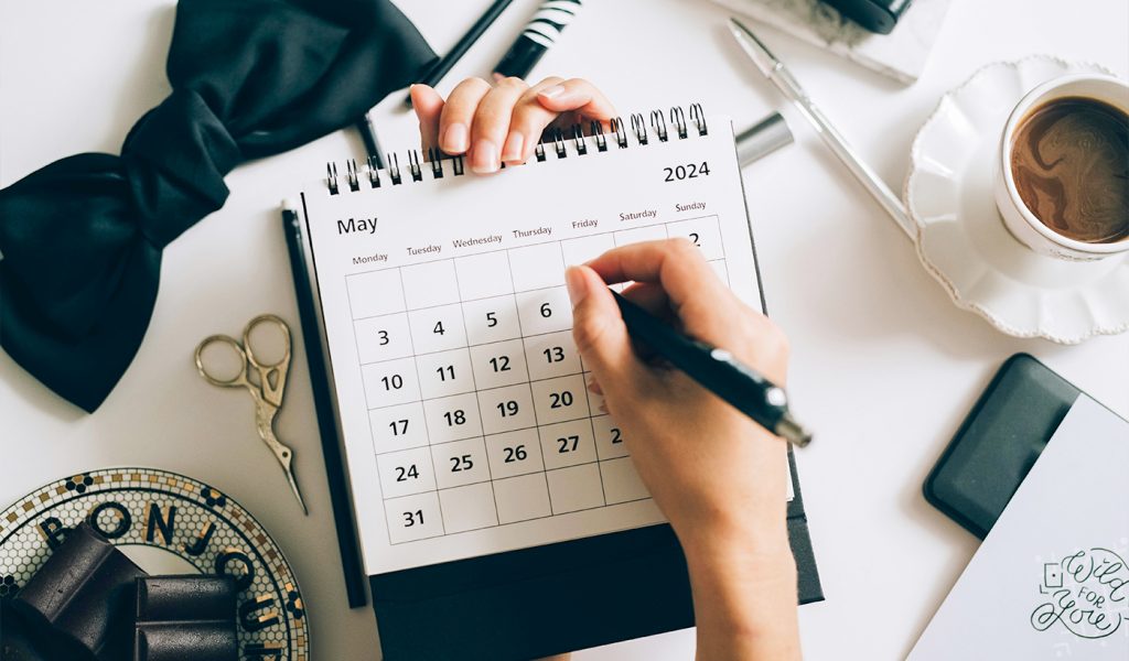 Person deciding on a book launch date with a calendar and cup of coffee