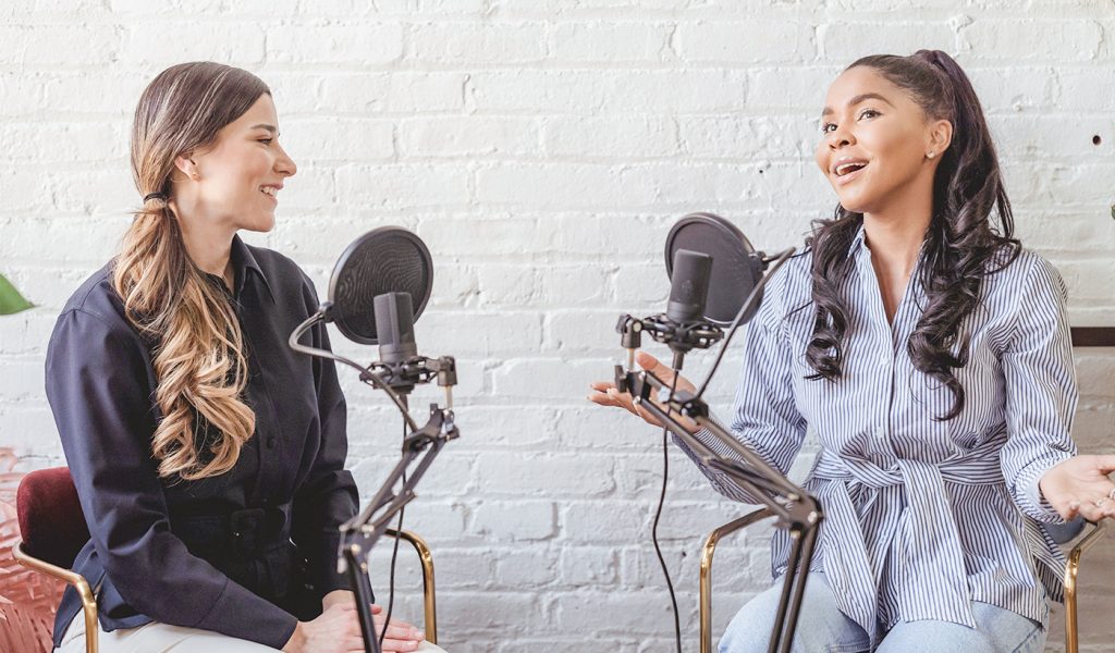 Two influencers chatting in front of microphones, talking about a book launch