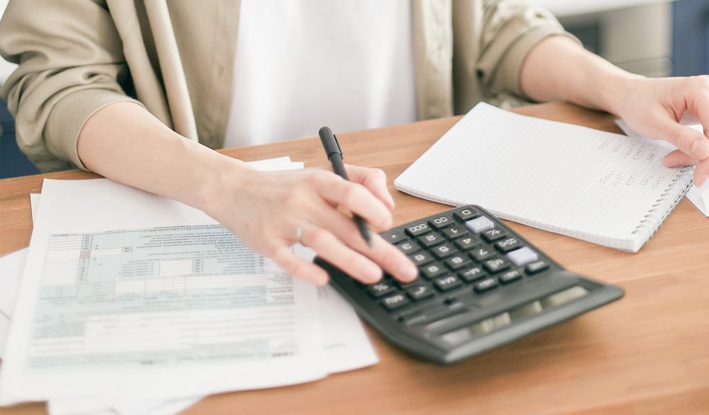 Person using a calculator to decide what paid advertising they can afford for their book launch