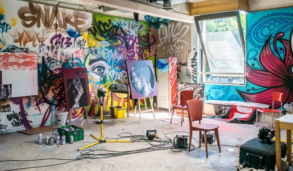 Artist's studio with lots of spray paint and painted canvases