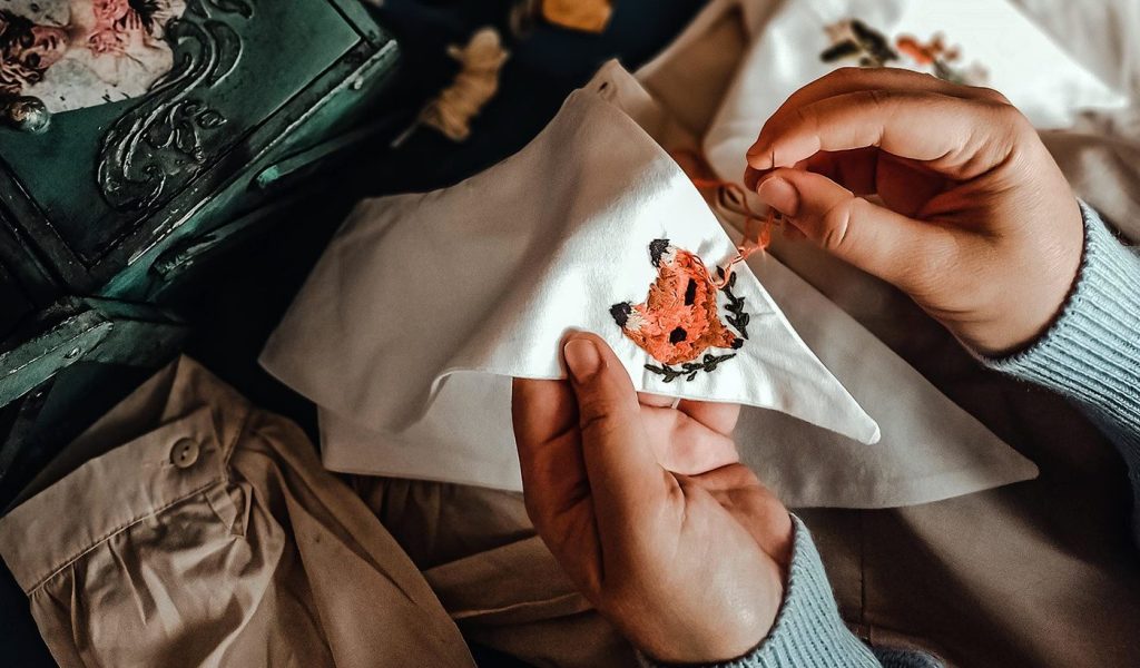 Person embroidering a fox creatively