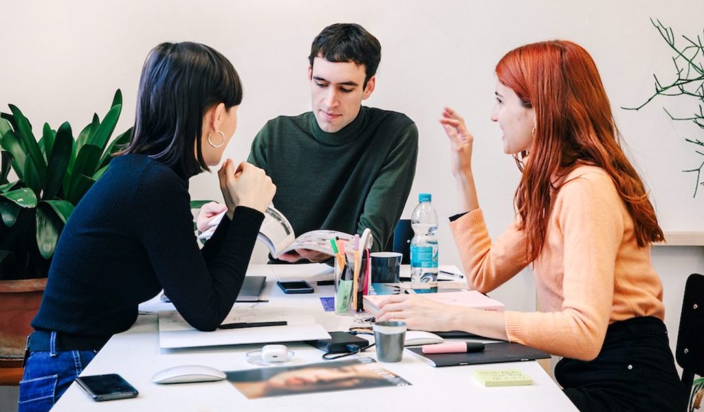 Three creative professionals chatting and looking at a magazine