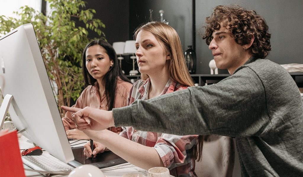 A group of people working together at a computer, trying to help each other get more and better creative ideas