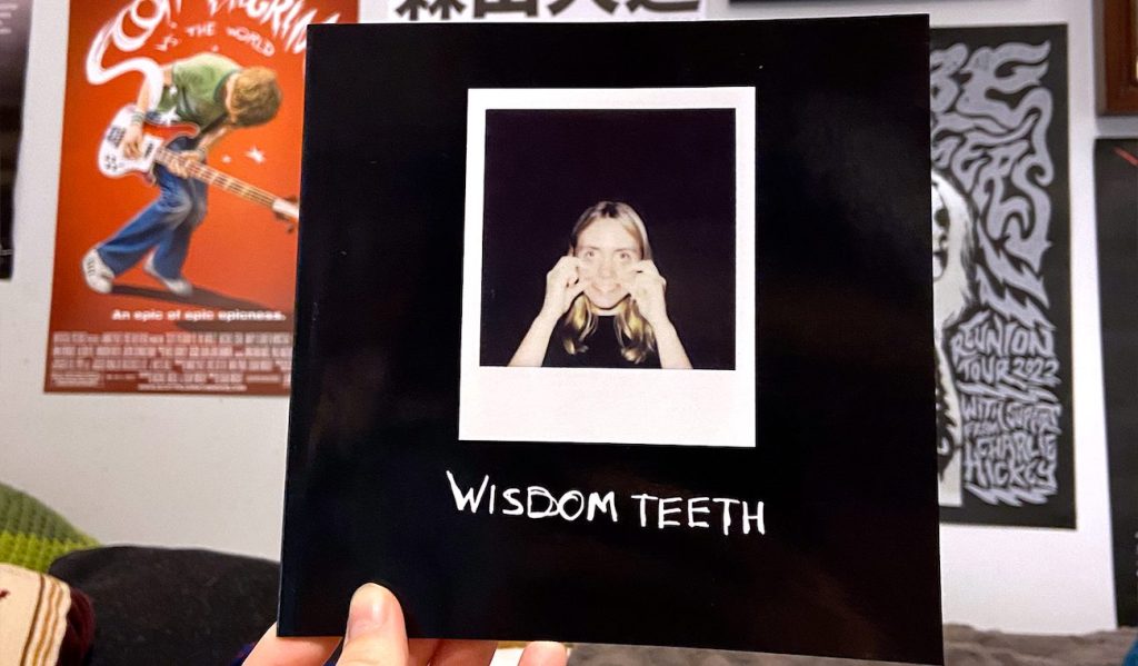 Close-up of Rose Boakes holding the Wisdom Teeth photography zine with a Polaroid-style photo on the cover