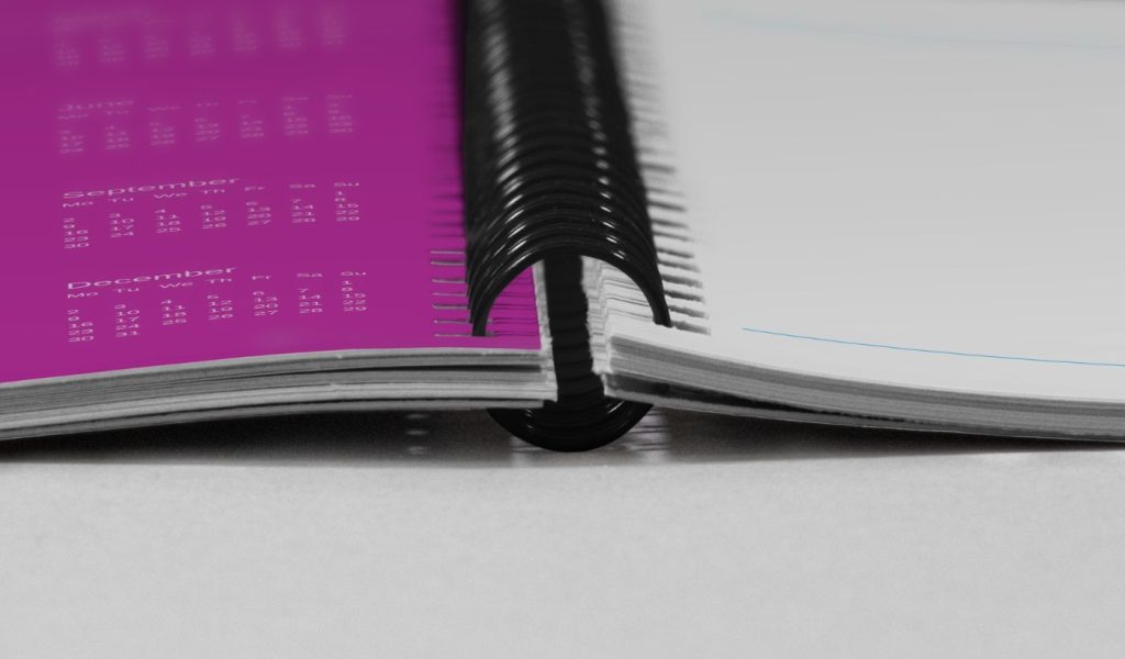 A close-up shot of a Wire-O softcover notebook open flat on a grey surface.